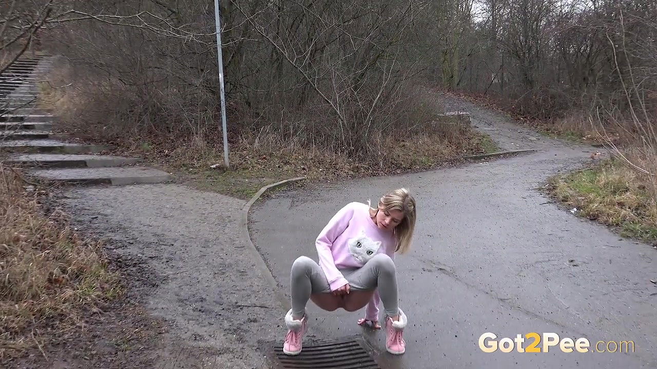 Blonde babe Claudia pisses down a drain outside