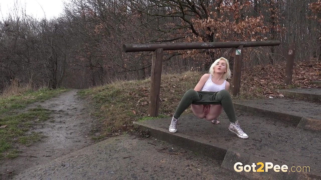 Blonde babe pisses outside on a muddy path