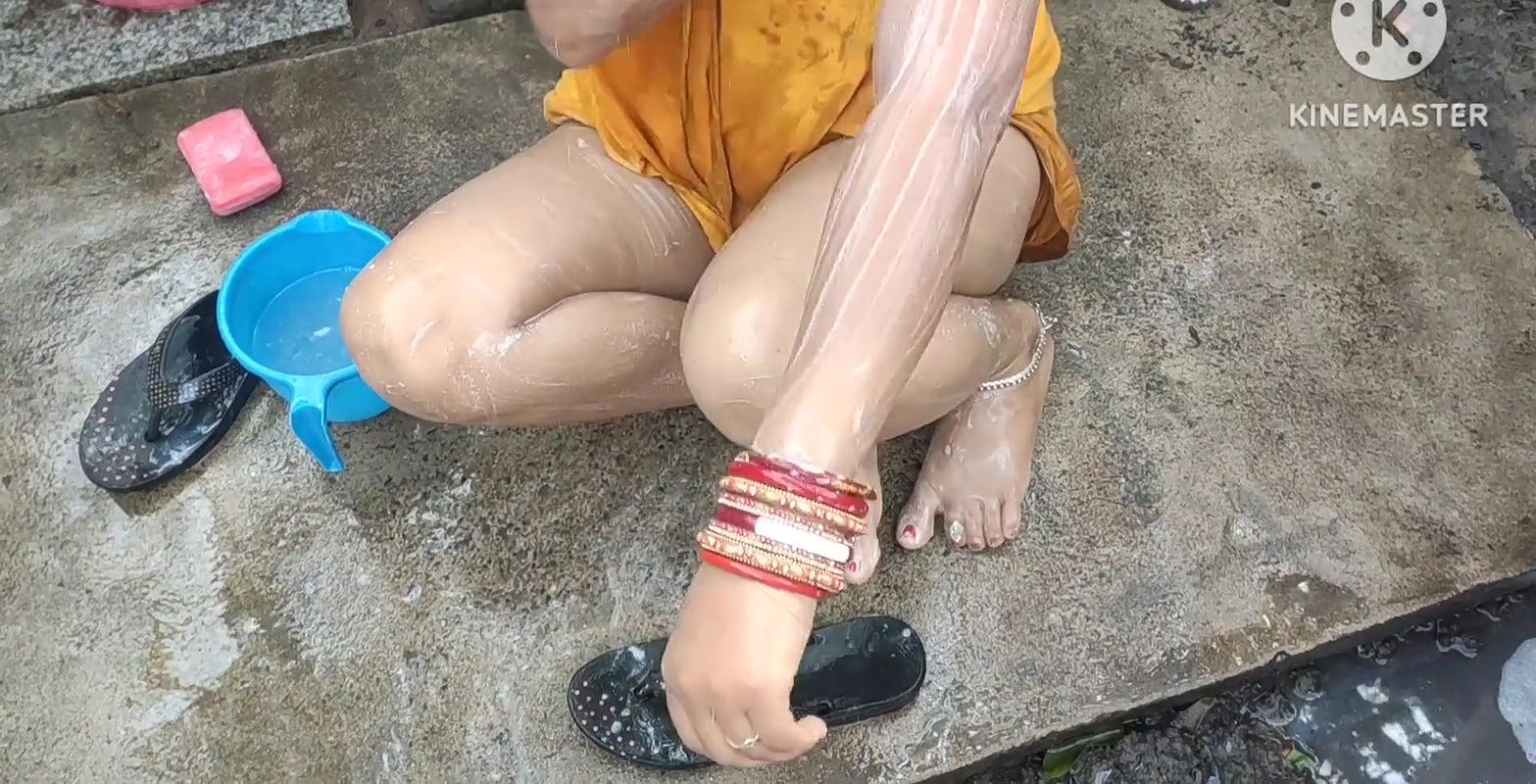 Indian house wife bathing outside with