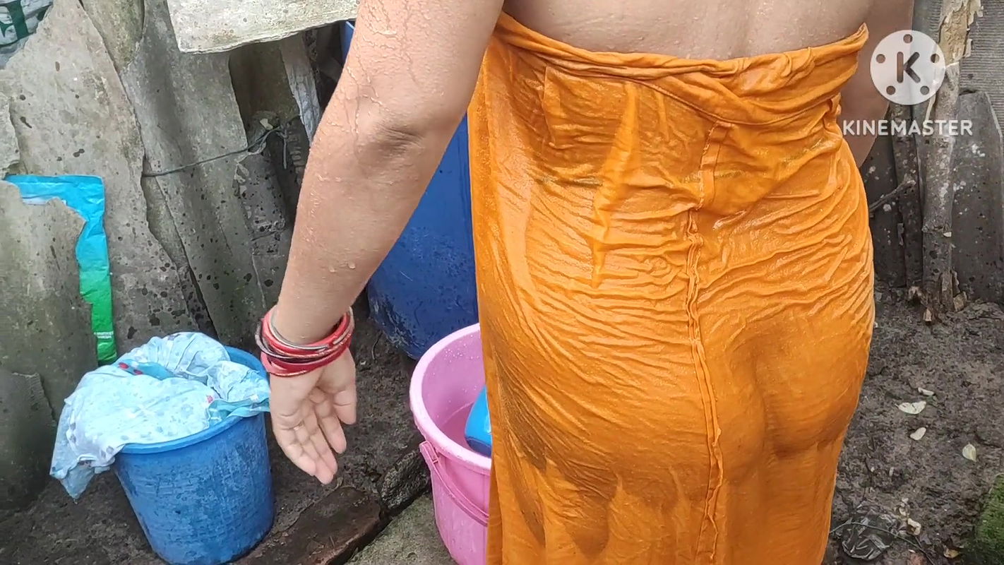 Indian house wife bathing outside with