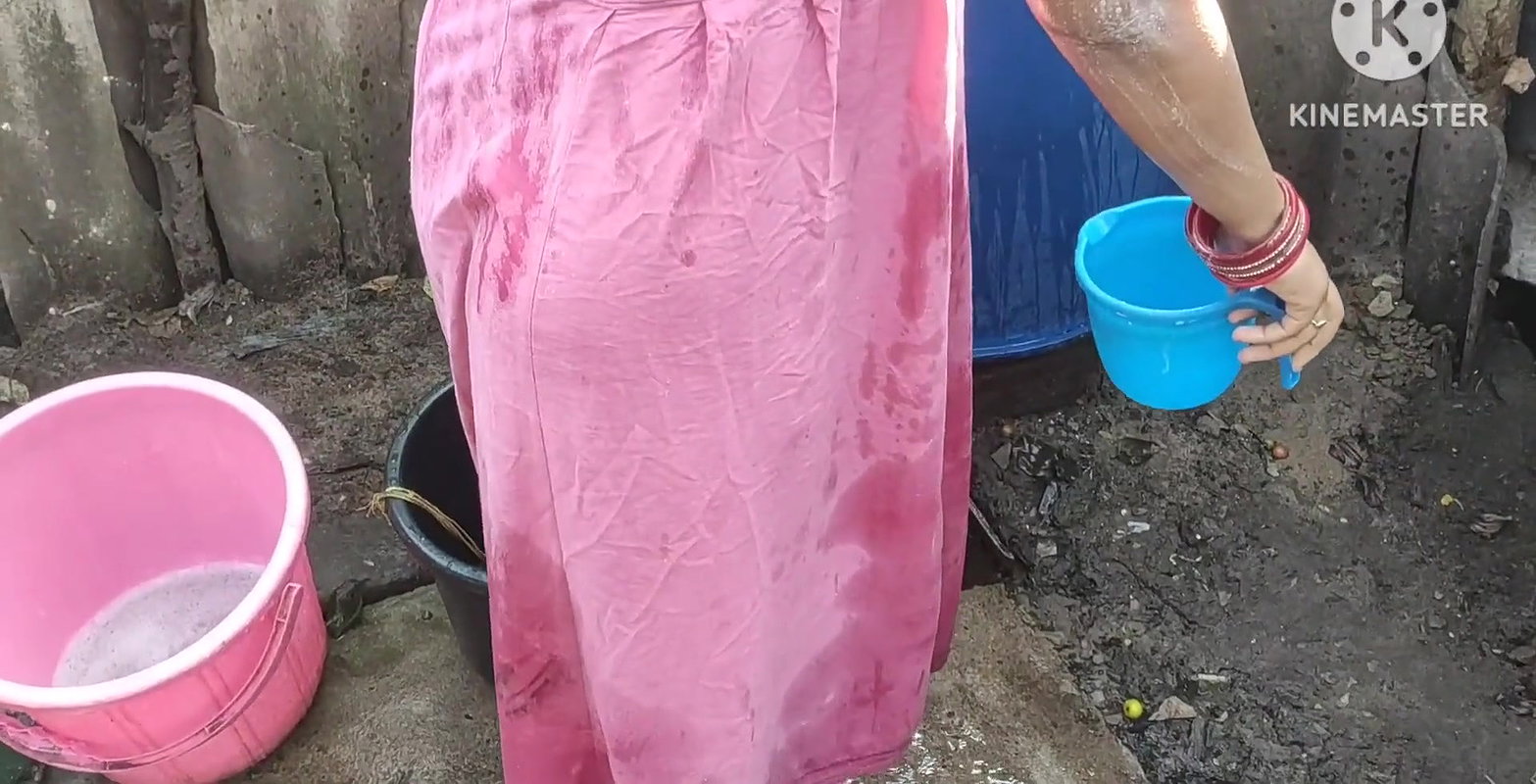 Indian house wife bathing outside with.