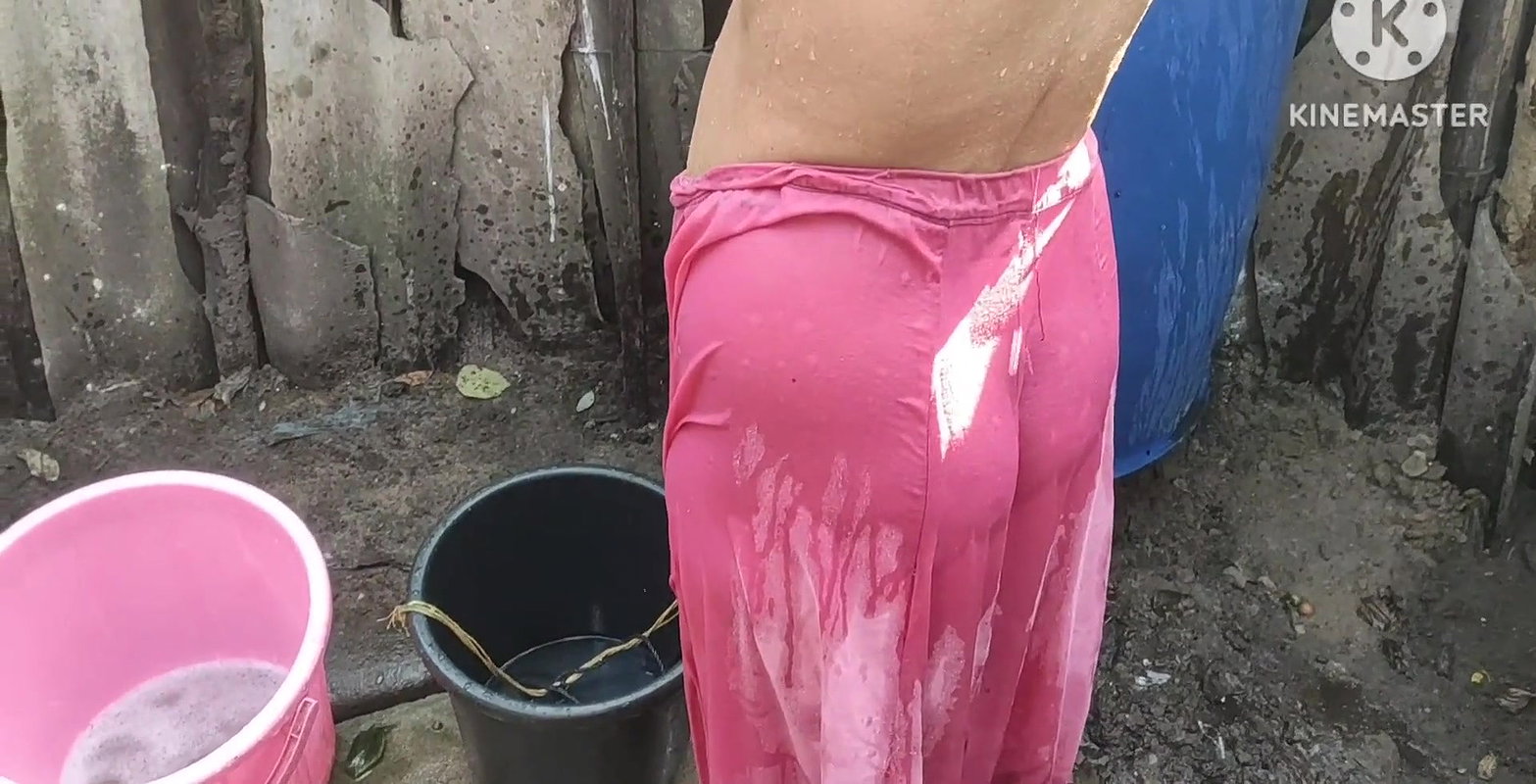 Indian house wife bathing outside with.